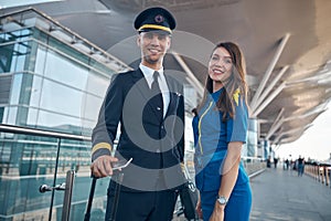 Cheerful pilot and stewardess standing on the street