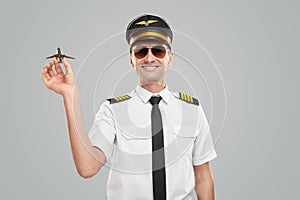 Cheerful pilot in uniform with toy airplane
