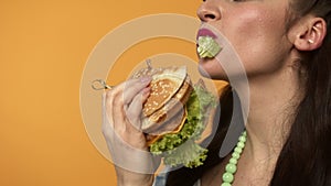 Cheerful pin up woman eating burger and winking at camera