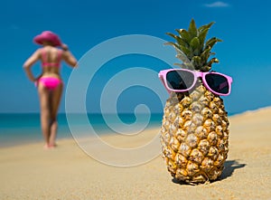 Cheerful pineapple glasses and a woman in a bikini sunbathing on the beach on sea backgrounde beach on sea background.