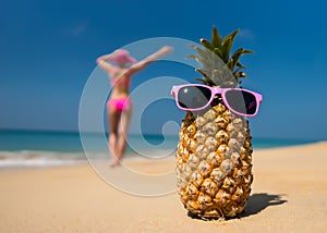 Cheerful pineapple glasses and a woman in a bikini sunbathing on the beach on sea backgrounde beach on sea background.