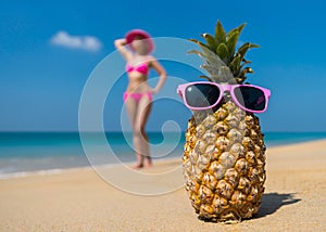 Cheerful pineapple glasses and a woman in a bikini sunbathing on the beach on sea backgrounde beach on sea background.