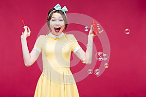 Cheerful pinup girl laughing and having fun with soap bubbles