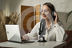 Cheerful podcaster woman recording her voice into a microphone. A female radio presenter broadcasts a podcast using a