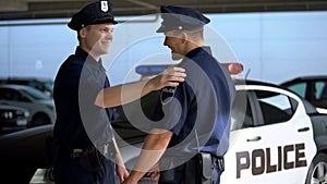 Cheerful policeman greeting mate against squad car, ready for patrolling, work