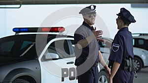 Cheerful policeman and policewoman giving high five to each other, teammates