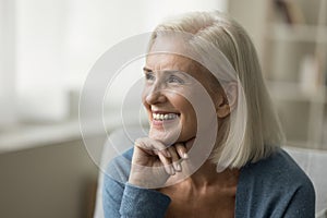 Cheerful positive blonde senior woman sitting on sofa