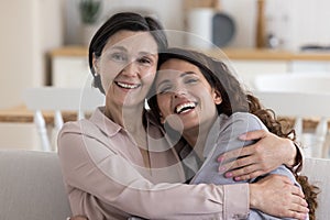 Cheerful positive mature 50s mom hugging adult daughter woman