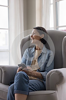 Cheerful positive middle aged woman thinking over text message