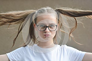 Cheerful positive pretty kid, teen age girl, being in great mood and showing her smile and long hair tails