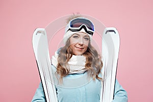 Cheerful positive young female skier is preparing to ski. Girl in equipment and with skis