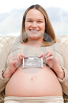 Cheerful pregnant woman holding an echography photo