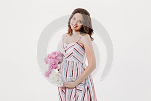 Cheerful pregnant woman holding flowers.