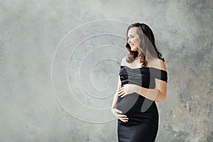 Cheerful pregnant woman portrait. Beautiful lady brunette wearing black dress smiling