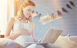 Cheerful pregnant woman surfing the Internet