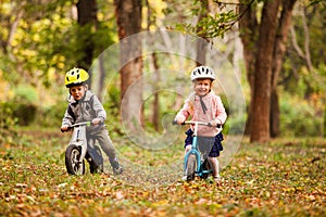 Cheerful preschool kids outdoors on balance bikes