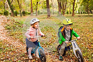 Cheerful preschool kids outdoors on balance bikes