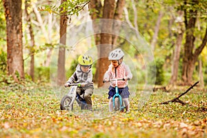 Cheerful preschool kids outdoors on balance bikes