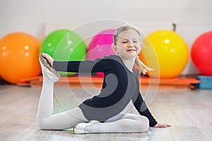 Cheerful preschooler girl doing gymnastics in the gym. The concept of sports, education, hobbies, training and dance
