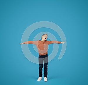 Cheerful Preteen Boy Spreading Hands, Pretending Flying Over Blue Background