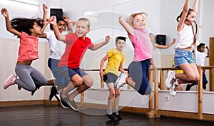 Cheerful preteen boys and girls jumping in dance class