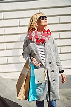 Cheerful pretty Caucasian female with paper multicolor shopping bags