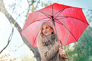 Cheerful pretty girl holding umbrella while strolling outside