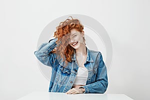 Cheerful pretty girl laughing looking at camera touching her red curly hair over white background.