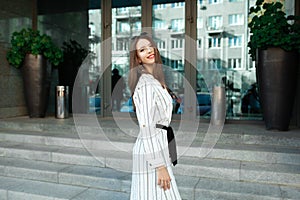 Cheerful pretty young lady entering glass door into modern office, hotel, cafe, business centre