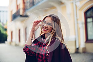 Cheerful pretty young lady holds his glasses her hands and smiles at his interlocutor.