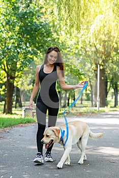 Cheerful pretty young woman walking and running with her dog in summer park. Active leisure, beautiful brunette girl at morning