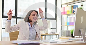 Cheerful professional woman laughs looking at computer monitor at desk in office