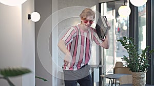 Cheerful redhead Caucasian young man dancing in slow motion to music from vintage tape recorder. Portrait of positive