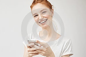 Cheerful redhead girl smiling holding phone.