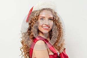 Cheerful redhead woman wearing Santa hat. Beautiful female model with long wavy hair and cute smile on white background