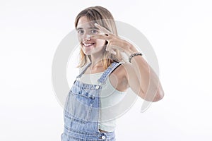 Cheerful redhead young woman model showing victory sign with fingers, eyes open on white background