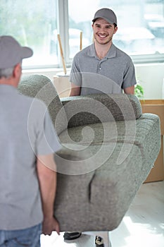 cheerful removals men carrying sofa