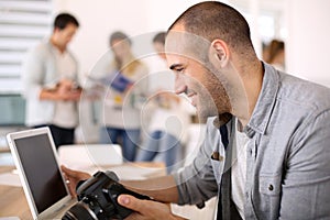 Cheerful reporter holding camera working on laptop