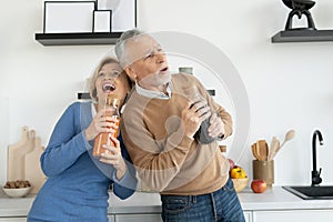 Cheerful retired couple holding glass jars and signing songs