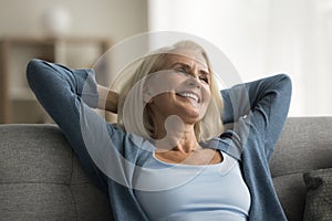 Cheerful retired elderly woman resting on home couch