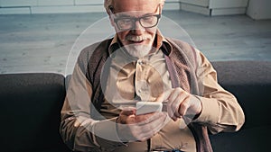 cheerful retired man in eyeglasses texting
