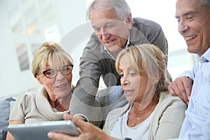 Cheerful retired people laughing and using tablet