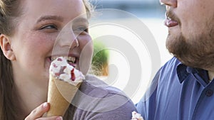 Cheerful romantic couple of obese people having fun and eating ice-cream on date