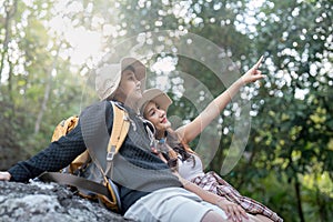 Cheerful romantic lesbian couple traveler with backpacks and siting relaxing while hiking in the mountains in summer