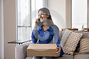 Cheerful satisfied young Indian consumer woman holding paper cardboard box