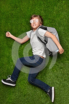 Cheerful school boy running to studies over lawn