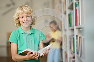 Cheerful schoolboy posing for the camera at the library