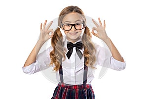 Cheerful schoolgirl shows ok gesture with fingers.