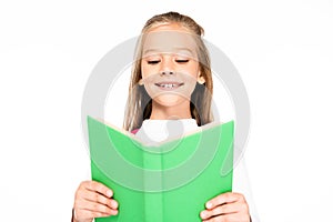 cheerful schoolgirl smiling while reading book isolated on white.