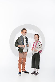 cheerful schoolkids standing with backpacks isolated